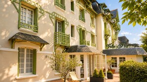 A building with green window frames, a sign reading 'Villa Floray,' and a paved courtyard with potted plants and outdoor seating. - Hôtel Villa Flornoy Pornichet Baie de la Baule (Pornichet)