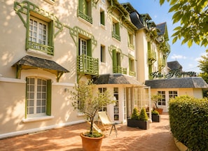 A building with green window frames, a sign reading 'Villa Floray,' and a paved courtyard with potted plants and outdoor seating. - Hôtel Villa Flornoy Pornichet Baie de la Baule (Pornichet)