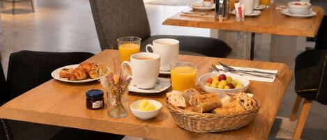 Uma mesa de café da manhã com croissants, frutas, café e suco de laranja.