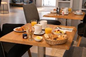 Ett frukostbord med croissanter, frukt, kaffe och apelsinjuice.