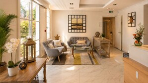 A spacious hotel lobby with a seating area, a reception desk, and a large window providing a view of the outdoors. - Hôtel Villa Flornoy Pornichet Baie de la Baule (Pornichet)
