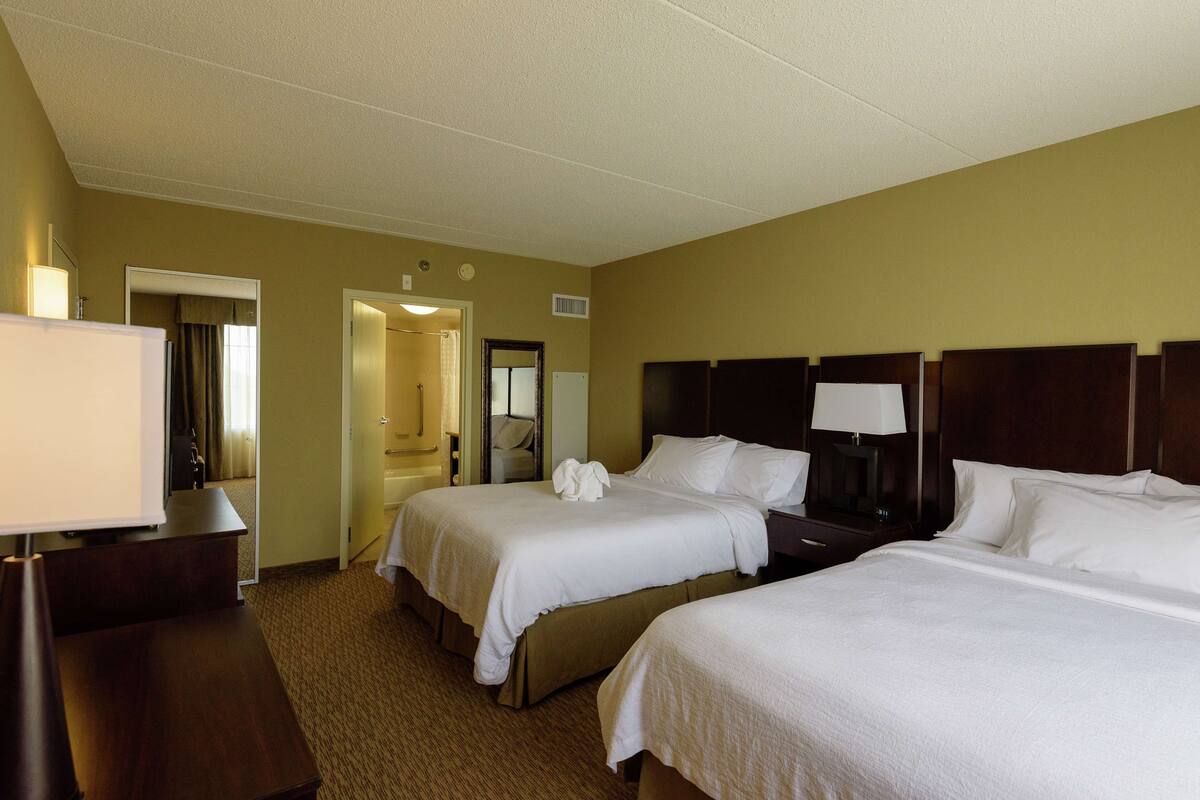 A hotel room with two beds, a desk, and a chair.