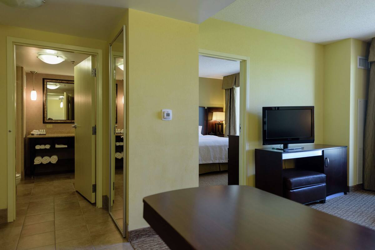 A hotel room with a television, a desk, and a bathroom visible through an open door.