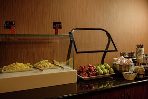 Un bufé con diversas frutas y una estación de café.