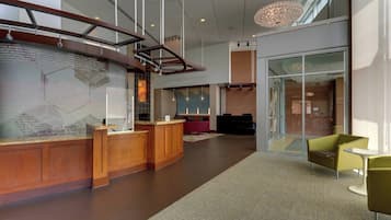 Een moderne lobby met een receptiebalie, een zithoek en grote ramen.