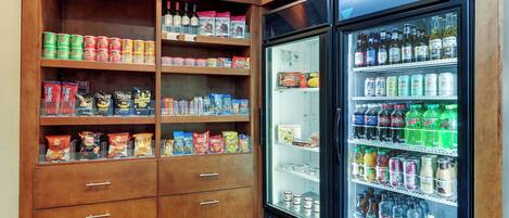A vending machine stocked with snacks and drinks, and a wooden cabinet with various food items.