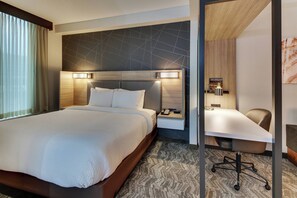 A hotel room with a large bed, a desk with a chair, and a nightstand with a phone. - SpringHill Suites Birmingham Downtown at UAB (Birmingham)