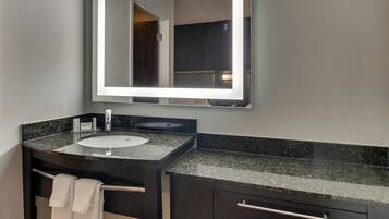 Un baño moderno con lavamanos de granito, un espejo grande y un perchero para toallas.