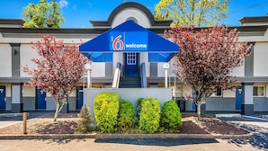 A hotel entrance with a '6 welcome' sign, a covered staircase, and a row of blue doors. - Motel 6 Toms River, NJ - Near Seaside Heights (Toms River)