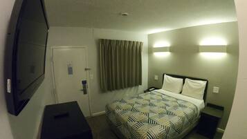 Een hotelkamer met een bed, een televisie, een bureau en een deur.