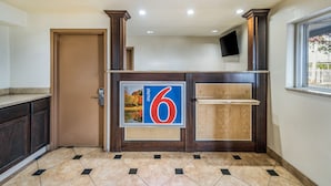 A hotel lobby with a reception desk, a wooden door, and a tiled floor. - Motel 6 Toms River, NJ - Near Seaside Heights (Toms River)