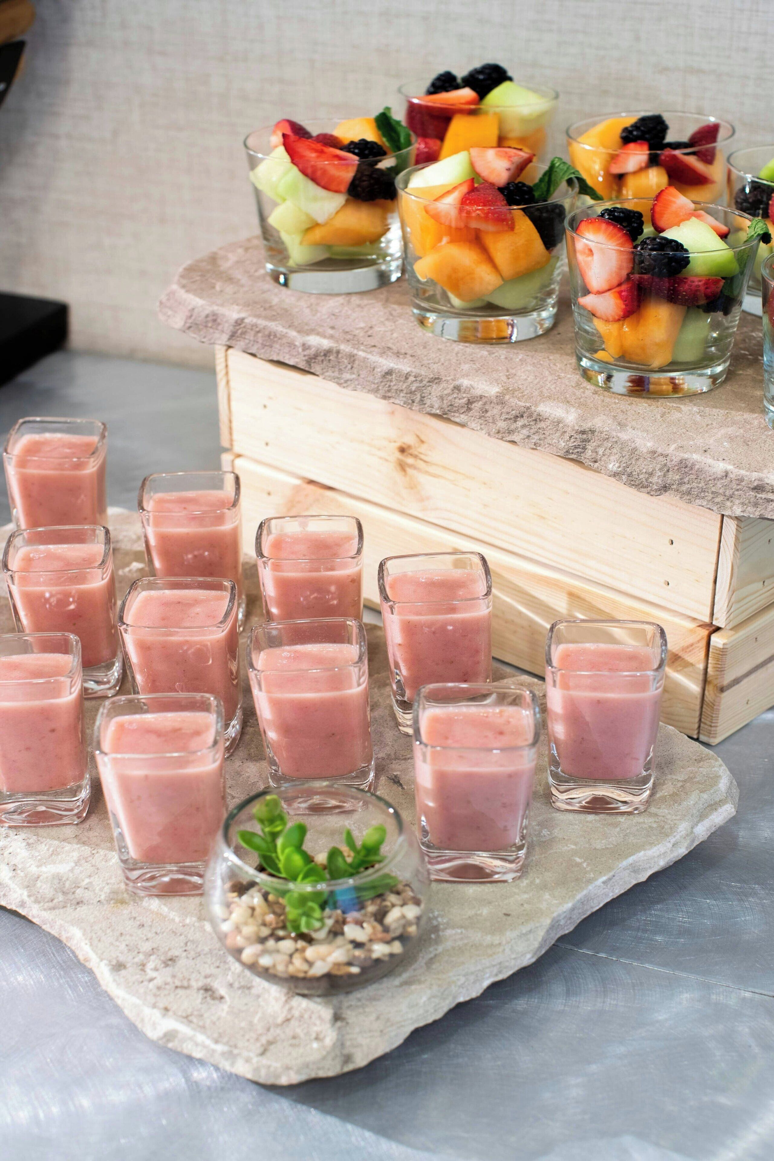 Esposizione di parfait alla frutta e smoothie su una superficie in pietra.