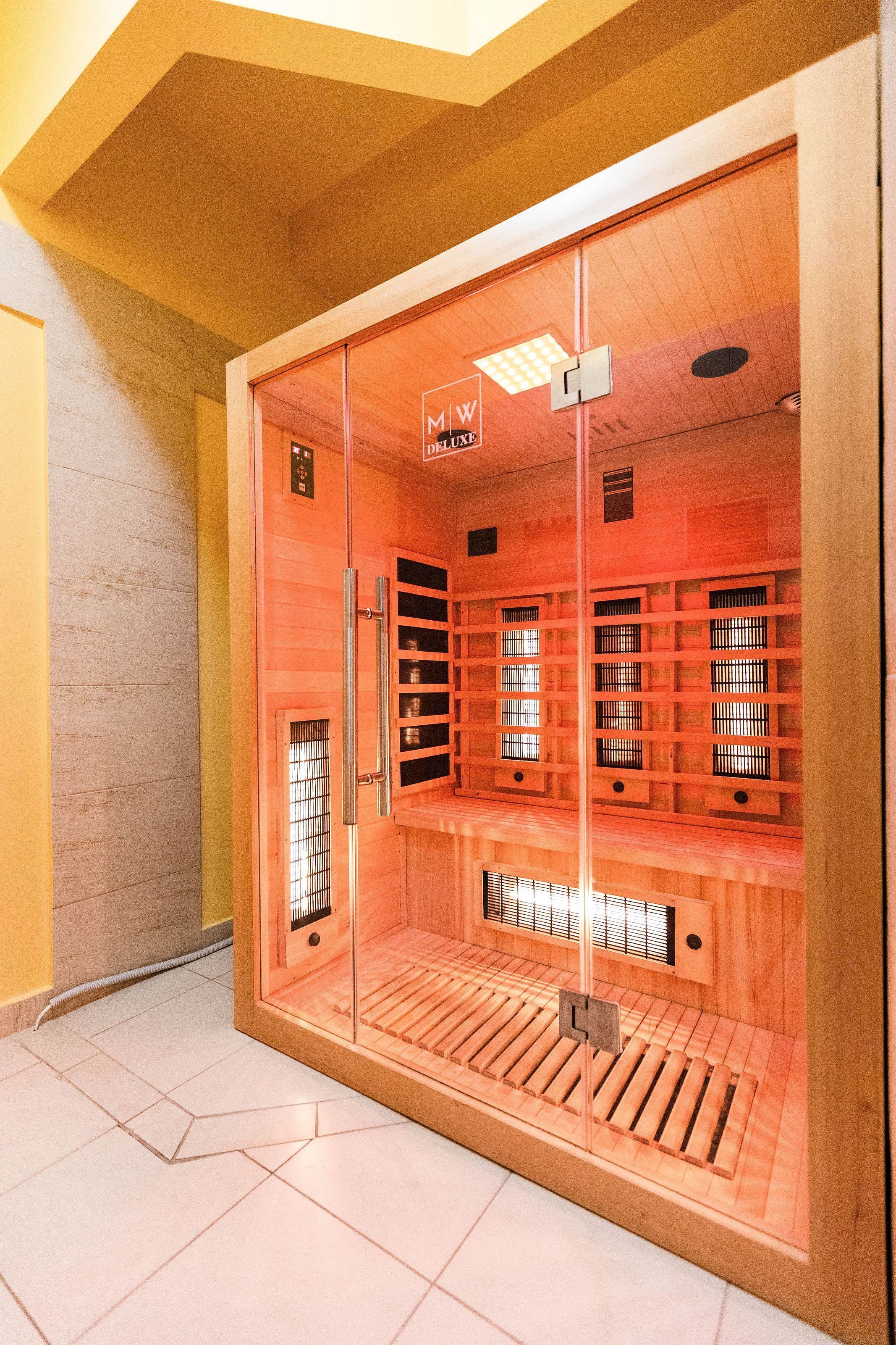 A sauna with a wooden interior, glass doors, and a tiled floor.