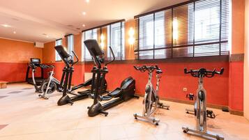 Un gimnasio con diverso equipo de ejercicio, incluyendo cintas de correr, elípticas y bicicletas estáticas.