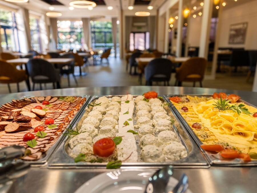 A buffet with various food options including meats, cheeses, and pasta.