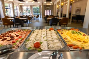 Un bufé con diversas opciones de comida, incluyendo carnes, quesos y pasta.