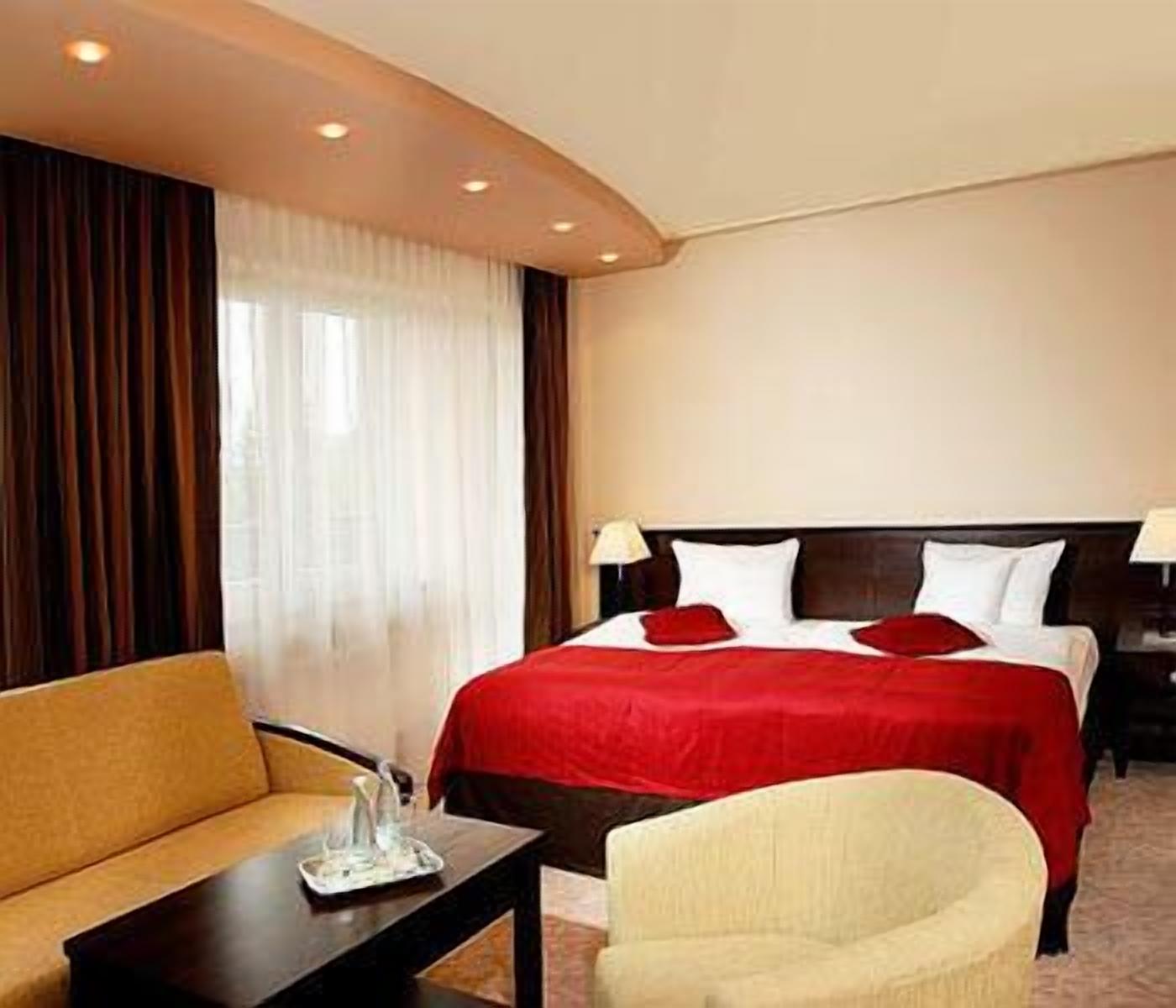 Una habitación de hotel con cama, sofá, sillón y mesita de noche.