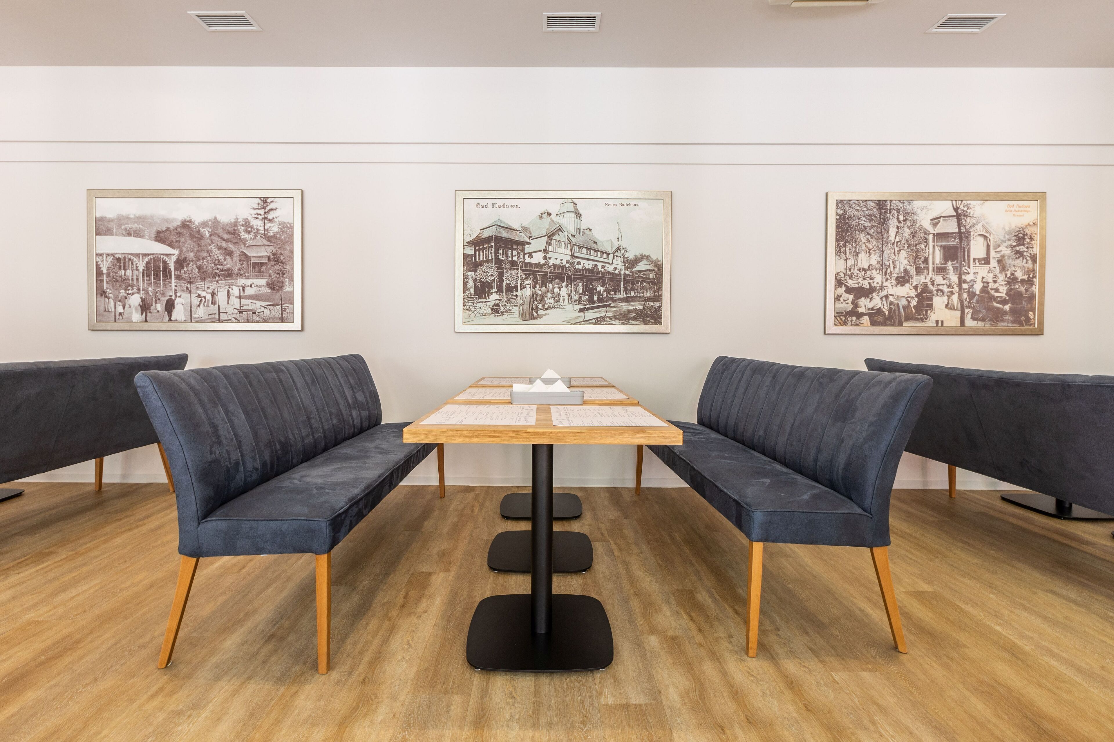 Een modern interieur met een houten tafel en twee donkerblauwe banken.