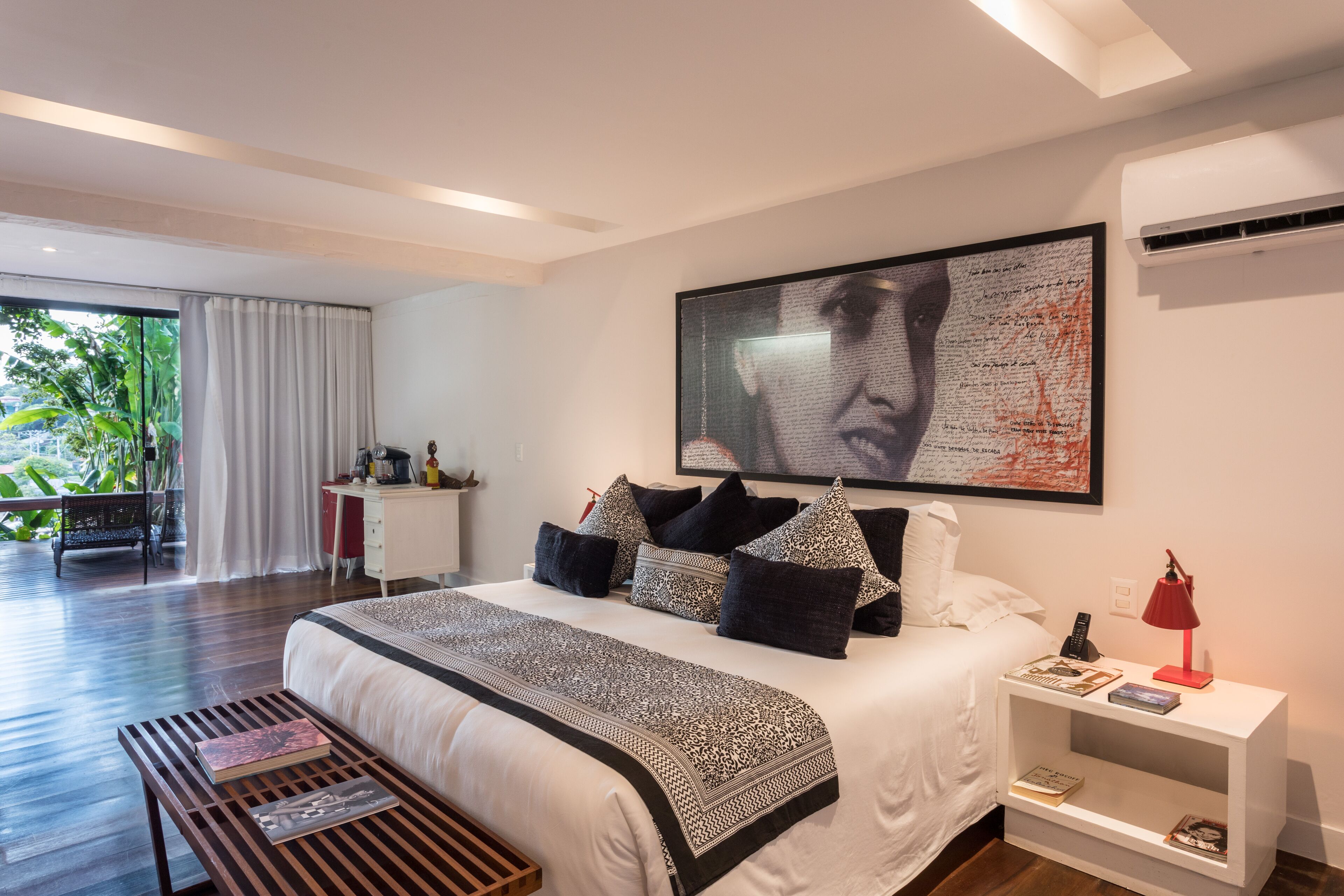 A modern bedroom with a large bed, bedside tables, and a view of the outdoors.
