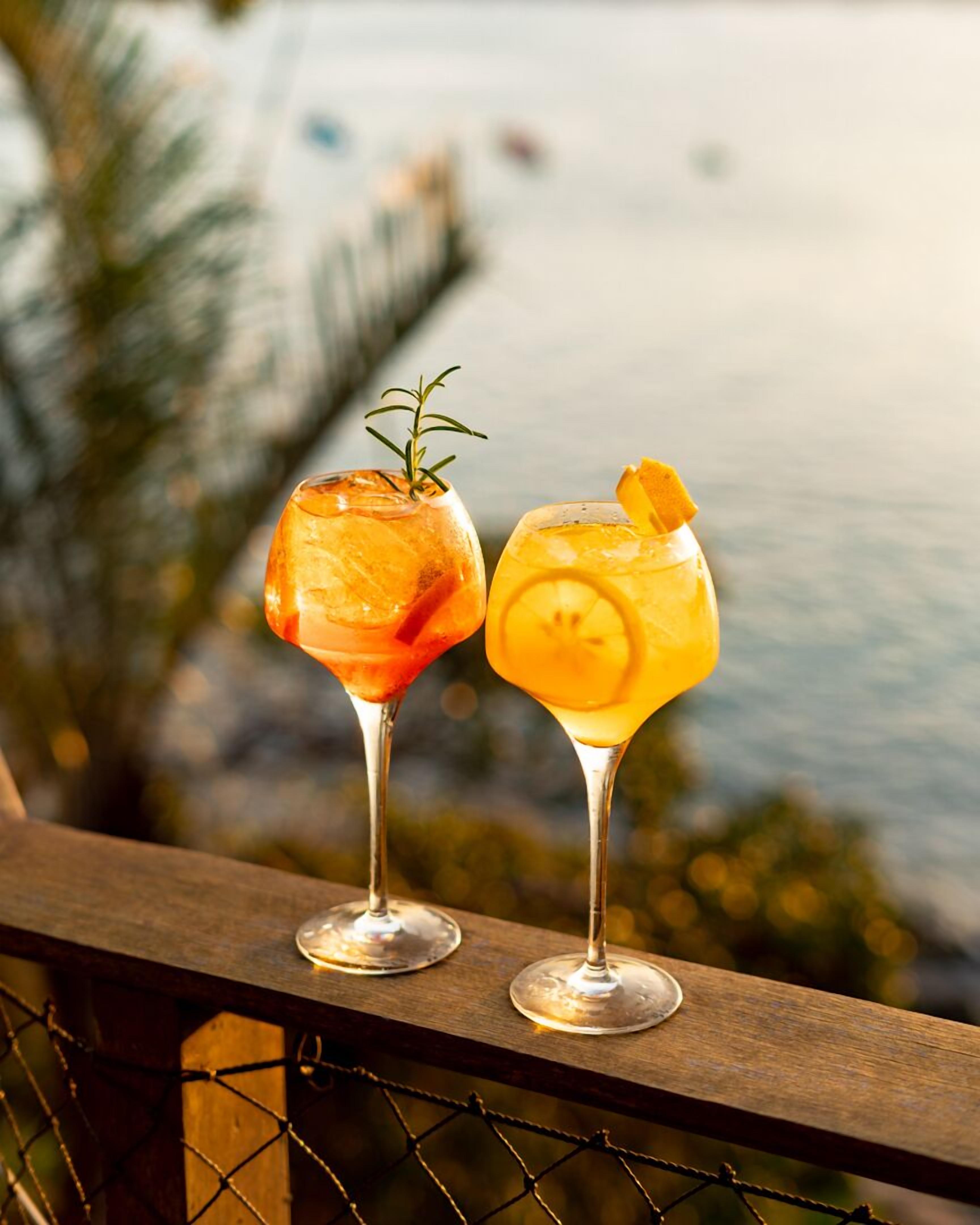 Deux cocktails sur un balcon avec vue sur un plan d’eau et un pont.