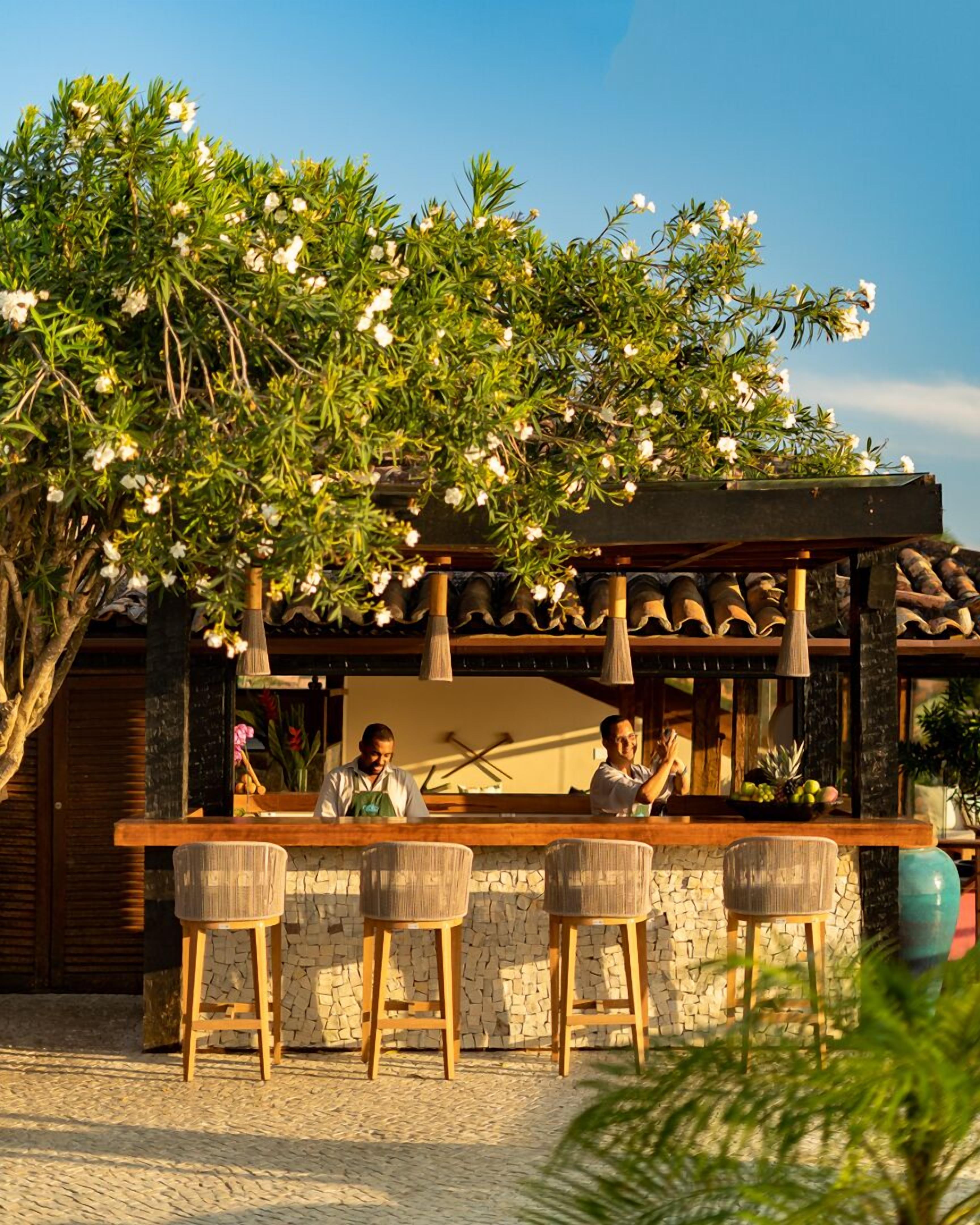 An outdoor bar area with a stone wall, wooden bar counter, and wicker chairs.