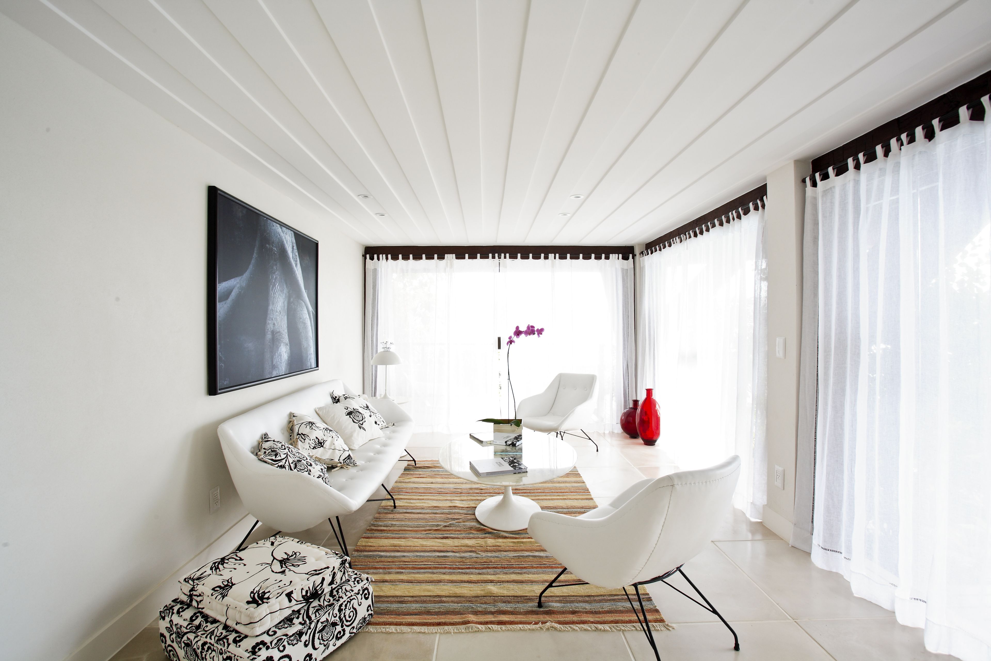 A modern living room with a white sofa, a coffee table, and a dining area.