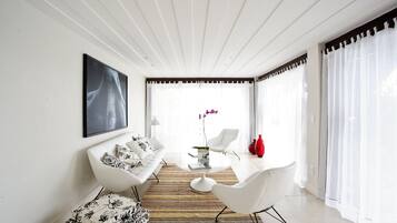 A modern living room with a white sofa, a coffee table, and a dining area.