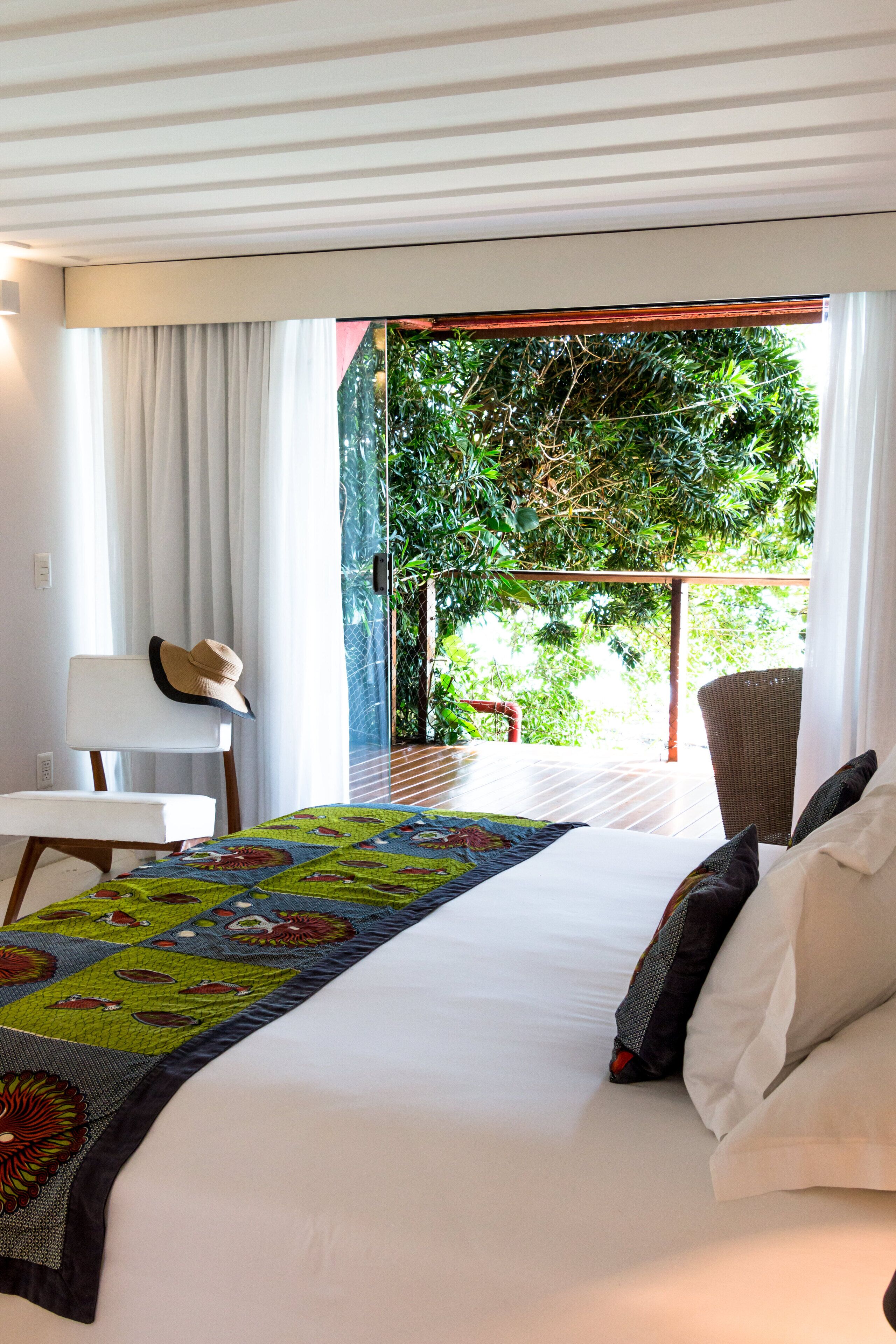 Une chambre d’hôtel avec un lit, une chaise, une table et une vue sur la verdure.