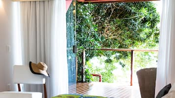 Une chambre d’hôtel avec un lit, une chaise, une table et une vue sur la verdure.