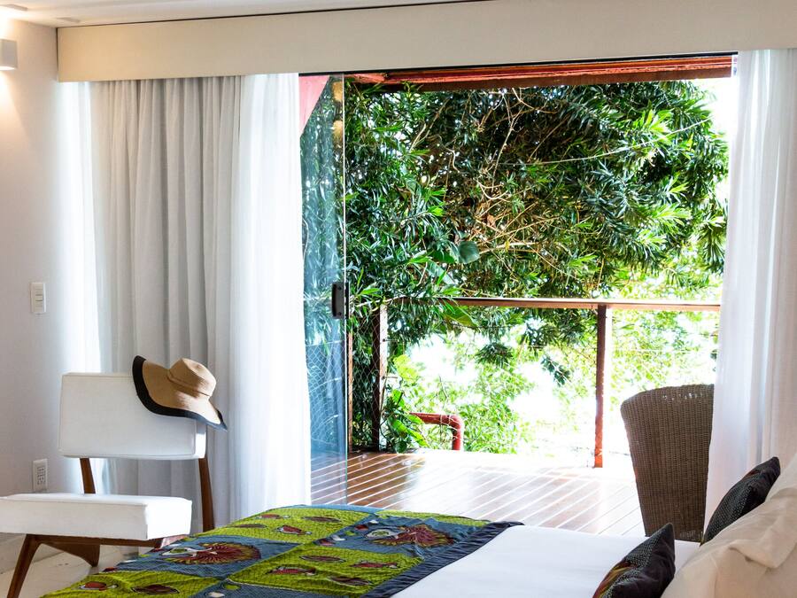 Une chambre d’hôtel avec un lit, une chaise, une table et une vue sur la verdure.
