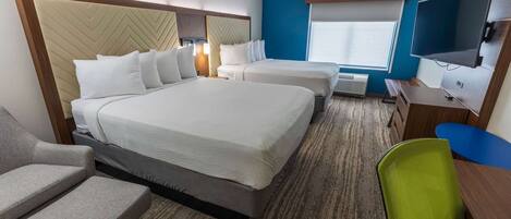 A hotel room with two beds, a TV, a desk, and a chair.