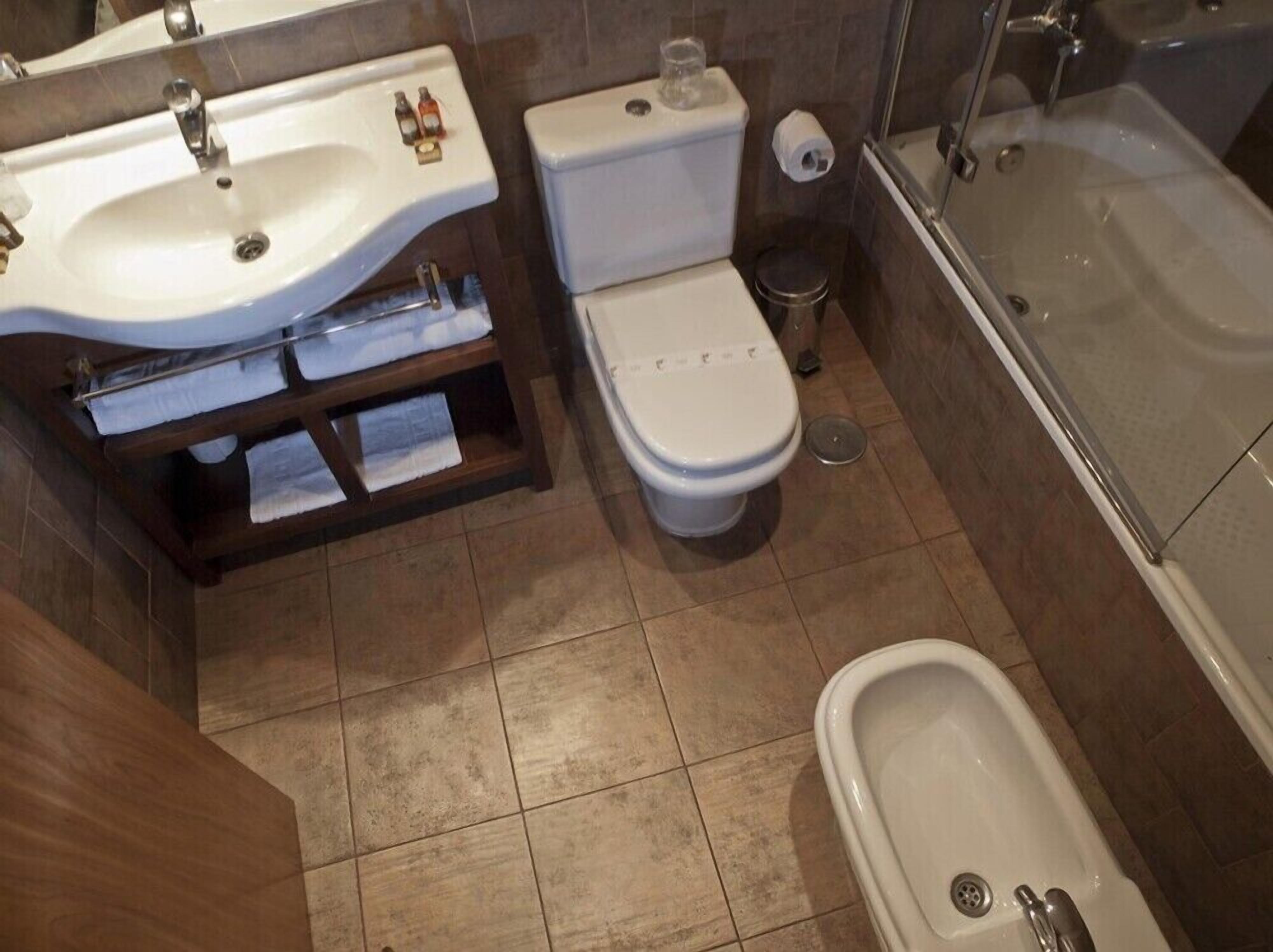 A bathroom with a sink, toilet, bidet, and bathtub.