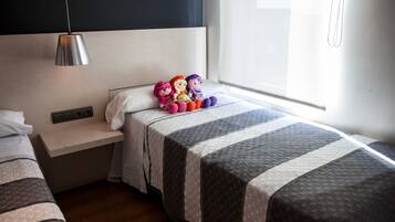 Habitación de hotel con dos camas, una mesita de noche, una lámpara y una ventana con cortinas.