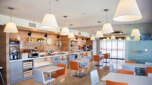 Un café moderne avec des meubles blancs et orange, de grandes suspensions et un mur d’accent en bois.