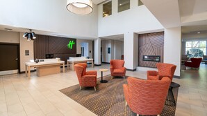 Een ruime lobby met een receptiebalie, zithoek en een groot raam.