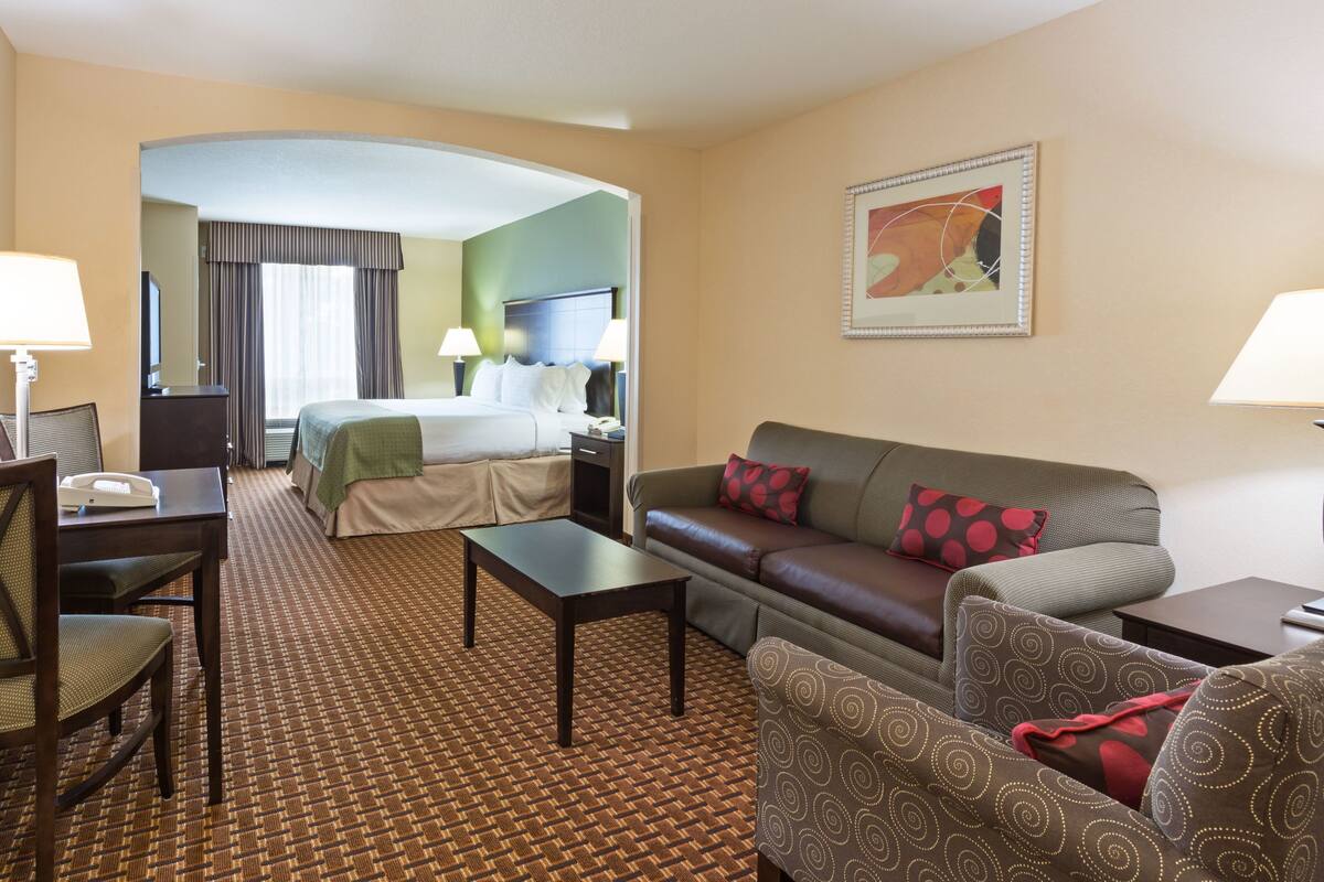 Ein Hotelzimmer mit Bett, Sofa, Couchtisch und Schreibtisch mit Lampe.