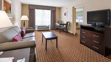 A hotel room with a sofa, a table, a TV, a desk, and a chair.