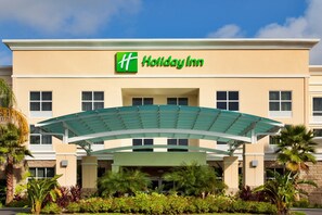 A Holiday Inn hotel with a green and white logo, a covered entrance, and palm trees. - Holiday Inn Daytona Beach LPGA Boulevard by IHG (Daytona Beach)