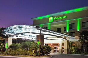 Un hotel Holiday Inn con entrada cubierta y fachada bien iluminada.