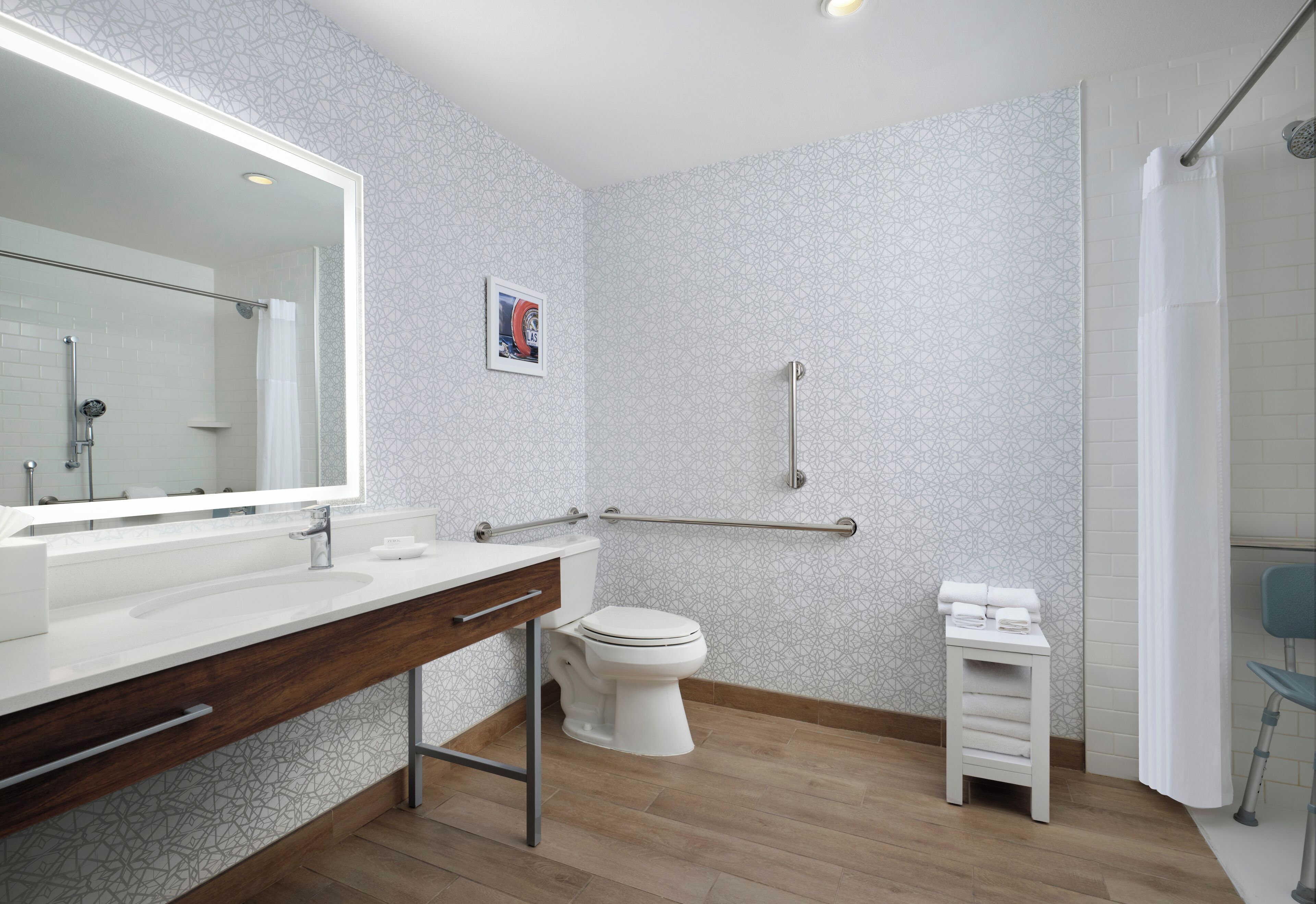 Un baño moderno con un espejo grande, lavabo blanco y retrete.