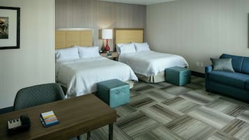 Habitación de hotel con dos camas, un escritorio, una silla, un sofá y un piso con diseño.