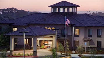 A hotel with a central courtyard, a flagpole with an American flag, and a sign indicating handicap accessibility.