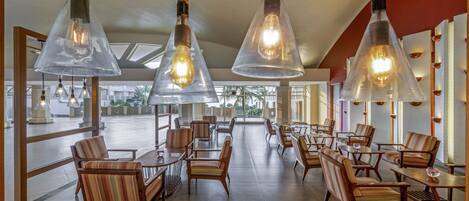 Un vaste espace dédié à la salle à manger, doté de meubles modernes et de luminaires suspendus en verre transparent.