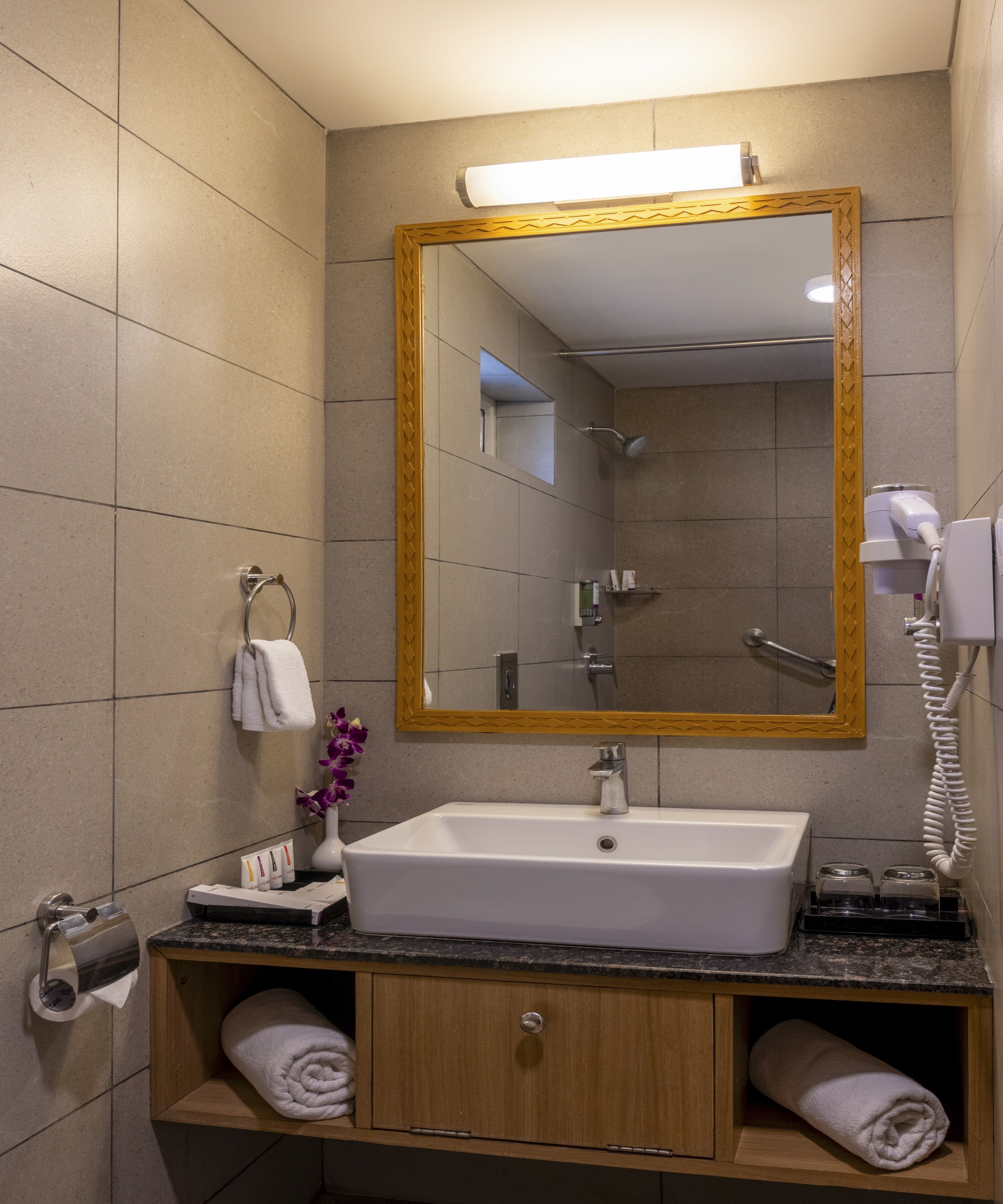 A bathroom with a sink, mirror, towel rack, and a shower.