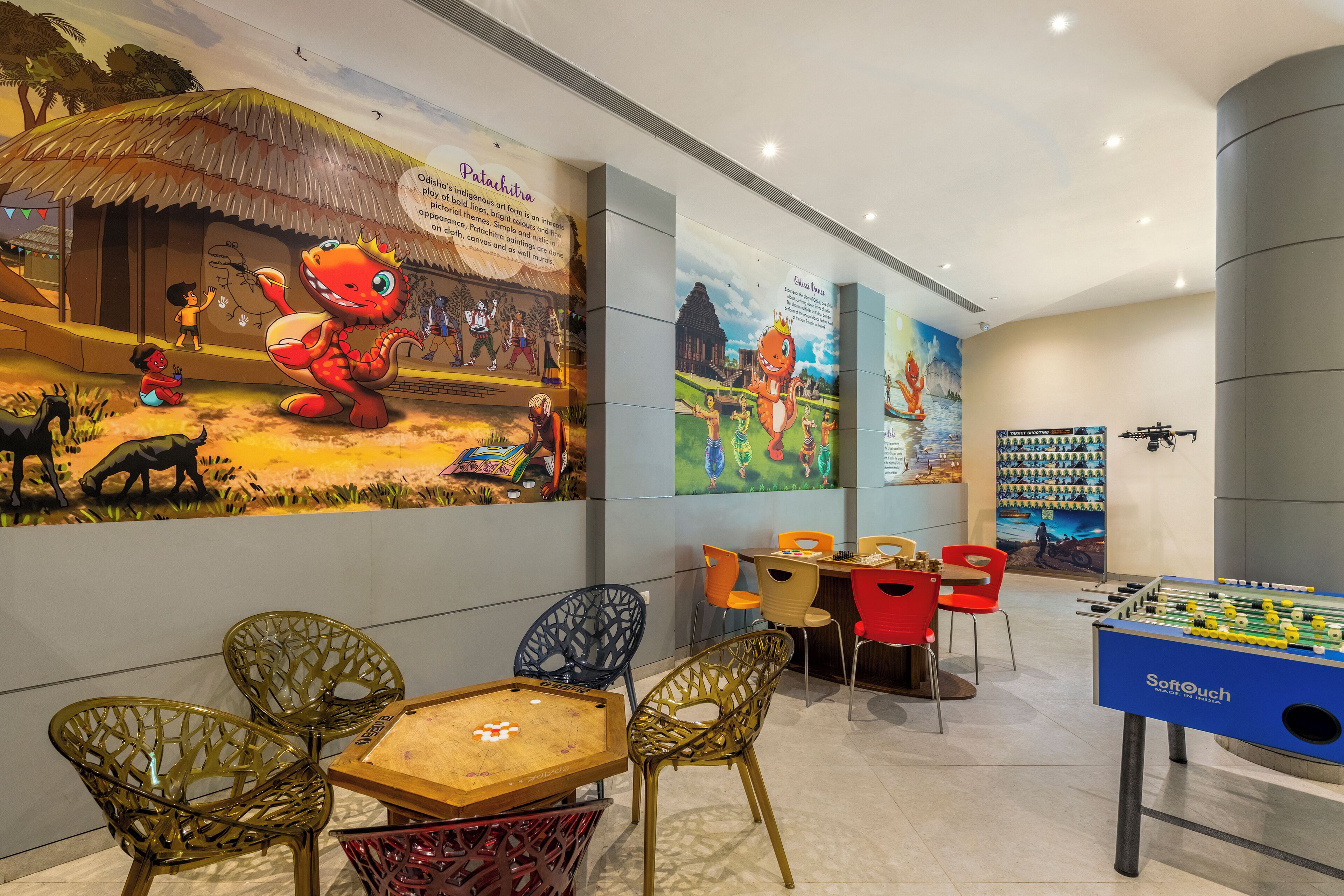 A children's play area with a foosball table, colorful chairs, and a mural depicting a traditional scene.