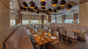 Un restaurant moderne avec des lambris en bois, plusieurs espaces de restauration et des luminaires suspendus.