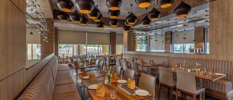 Un restaurant moderne avec des lambris en bois, plusieurs espaces de restauration et des luminaires suspendus.