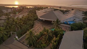 Un complexe hôtelier comprenant plusieurs bâtiments de style bungalow, une piscine et offrant une vue sur la plage.