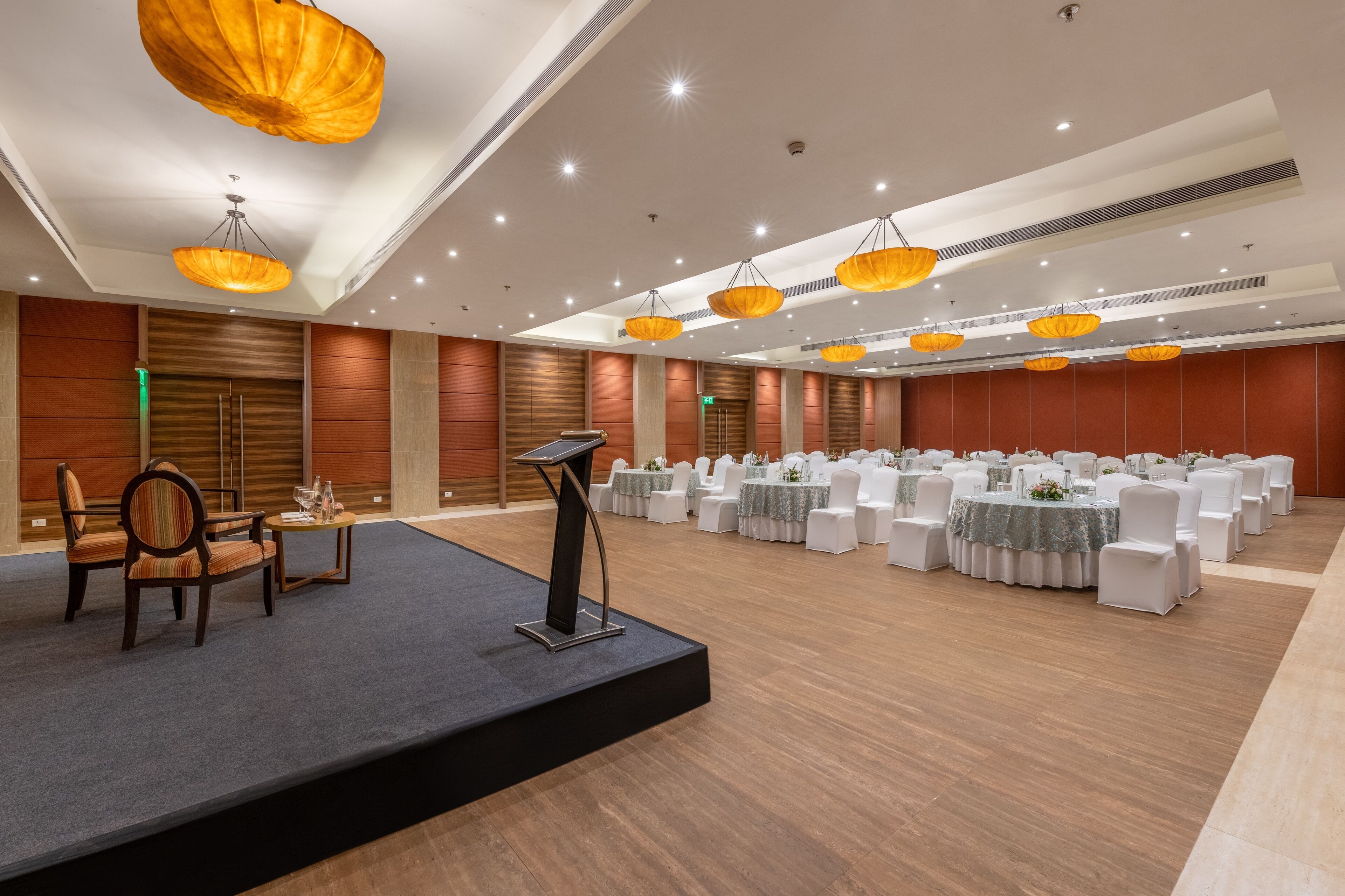 A conference room with a stage, white chairs, and tables set up for a meeting.