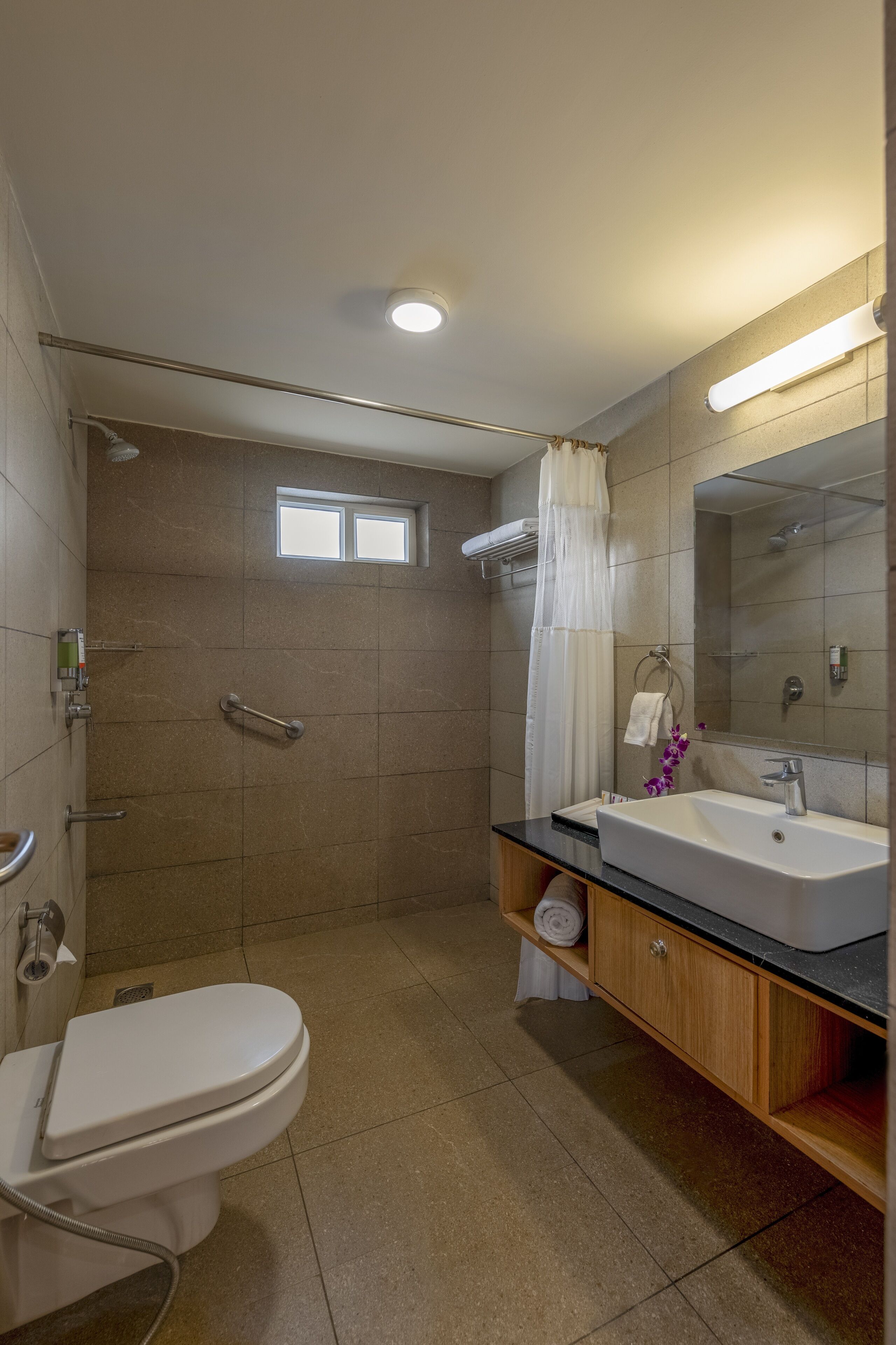 A modern bathroom with a shower, toilet, sink, and vanity.
